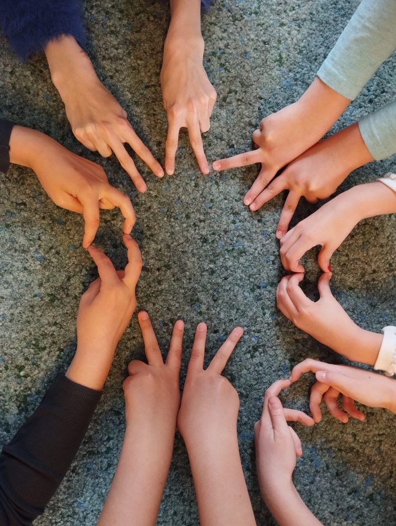 12 Hände im Kreis auf dem Fußboden, Finger zeigen aufeinander