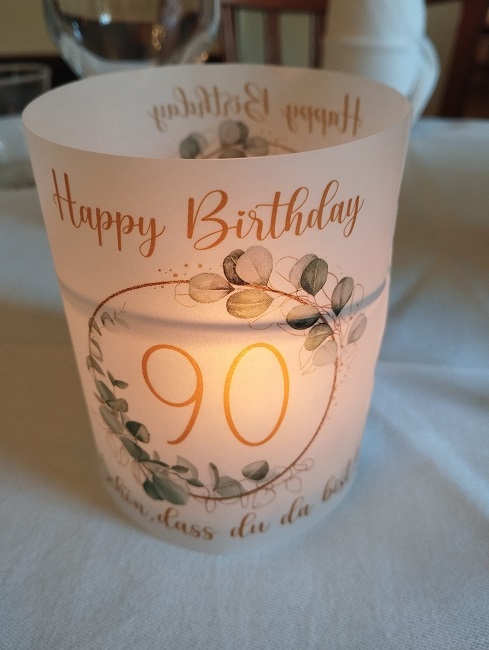 Glas mit einer 90 in einem Blätterkranz und einer Kerze drinnen