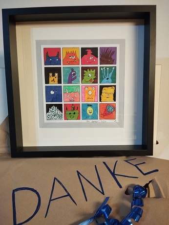 Bilderrahmen mit  kleine Quadraten darin gezeichnete Monster davor ein Geschenk mit Danke