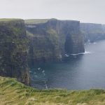 links grasbewachsene Klippen rechts Meer