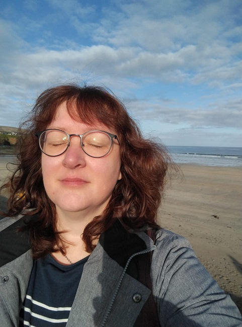 Frau mit geschlossenen Augen dahinter Meer