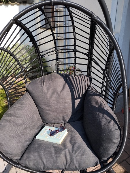 Hängesessel mit Kissen einem Buch und Sonnenbrille