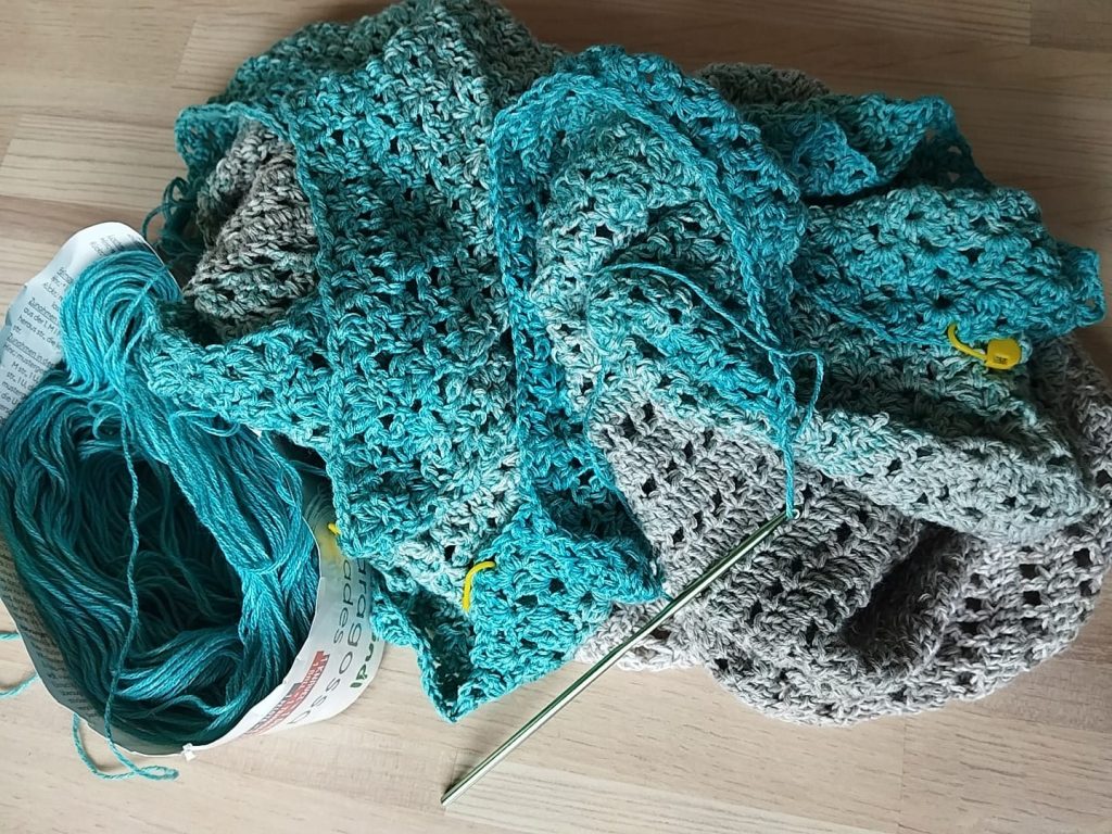 links Wolle daneben ein gehäkeltes Tuch