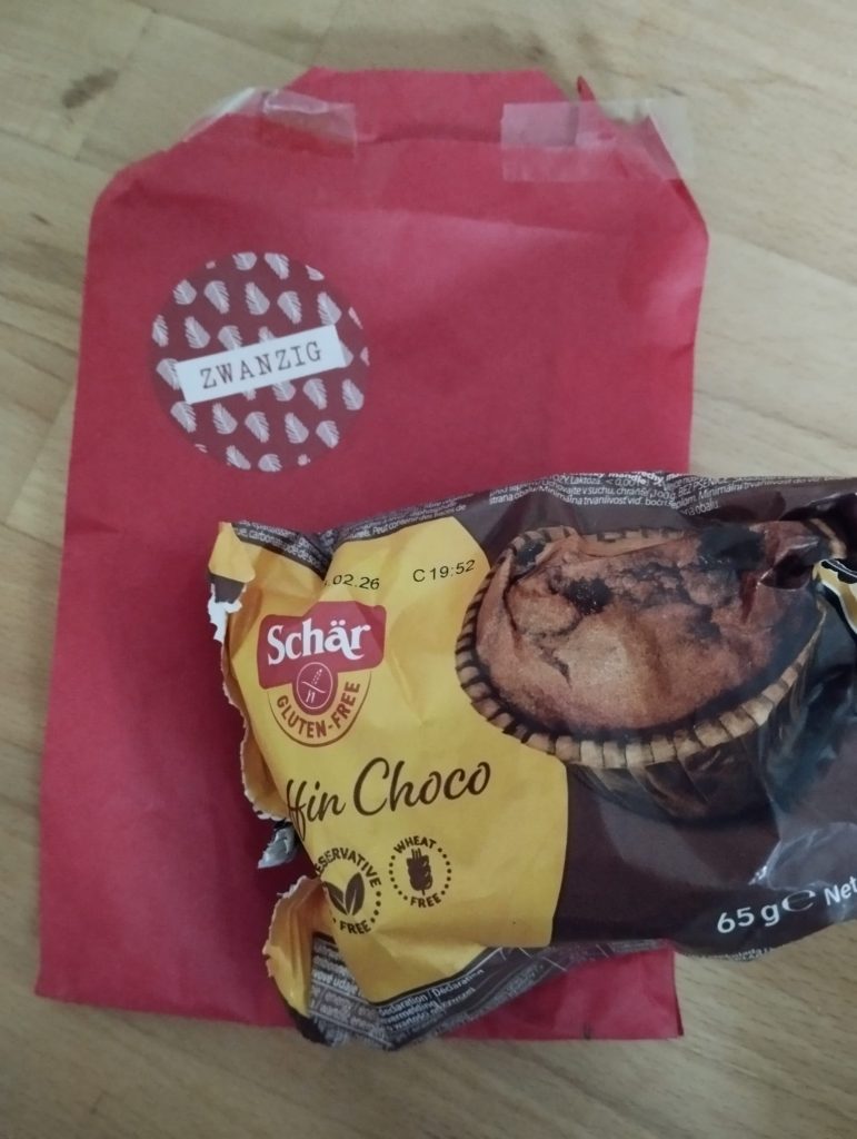 Tüte mit der Zahl 20 darauf ein Schoko-Muffin von Schär
