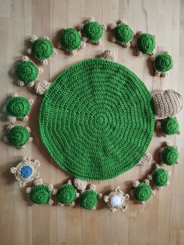 in der Mitte eine große gehäkelte Schildkröte, drum herum 18 kleine gehäkelte Schildköten