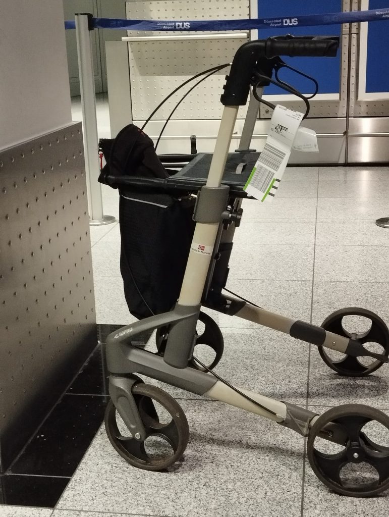 Rollator mit Flughafenschild am Griff