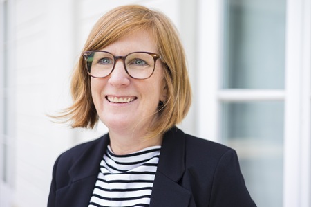 Frau mit Brille schaut lachend in die Kamera