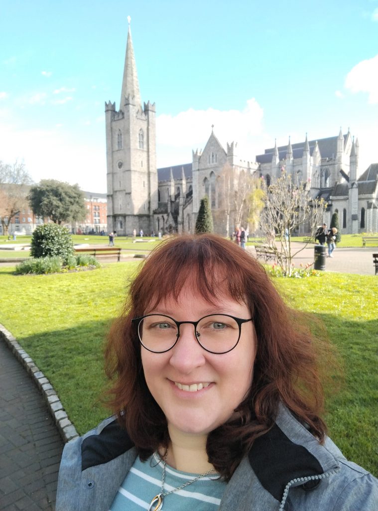 Frau schaut in die Kamera im Hintergrund die St. Patricks Catherdral in Dublin