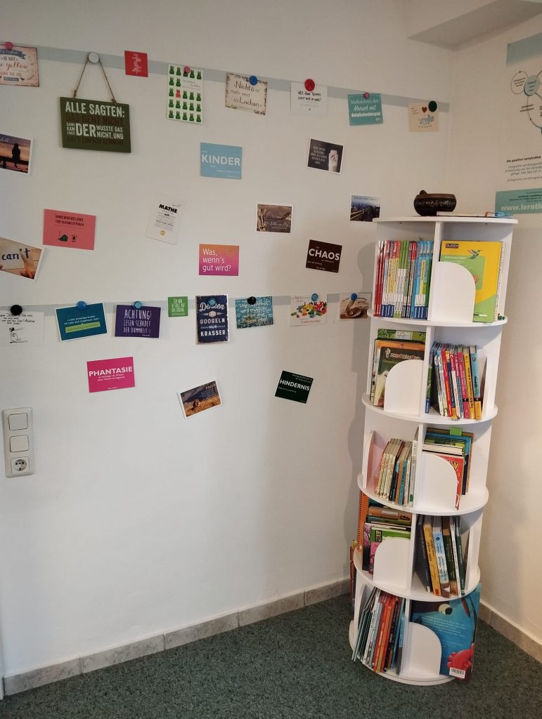 Wand mit Postkarten und ein rundes Bücherregal