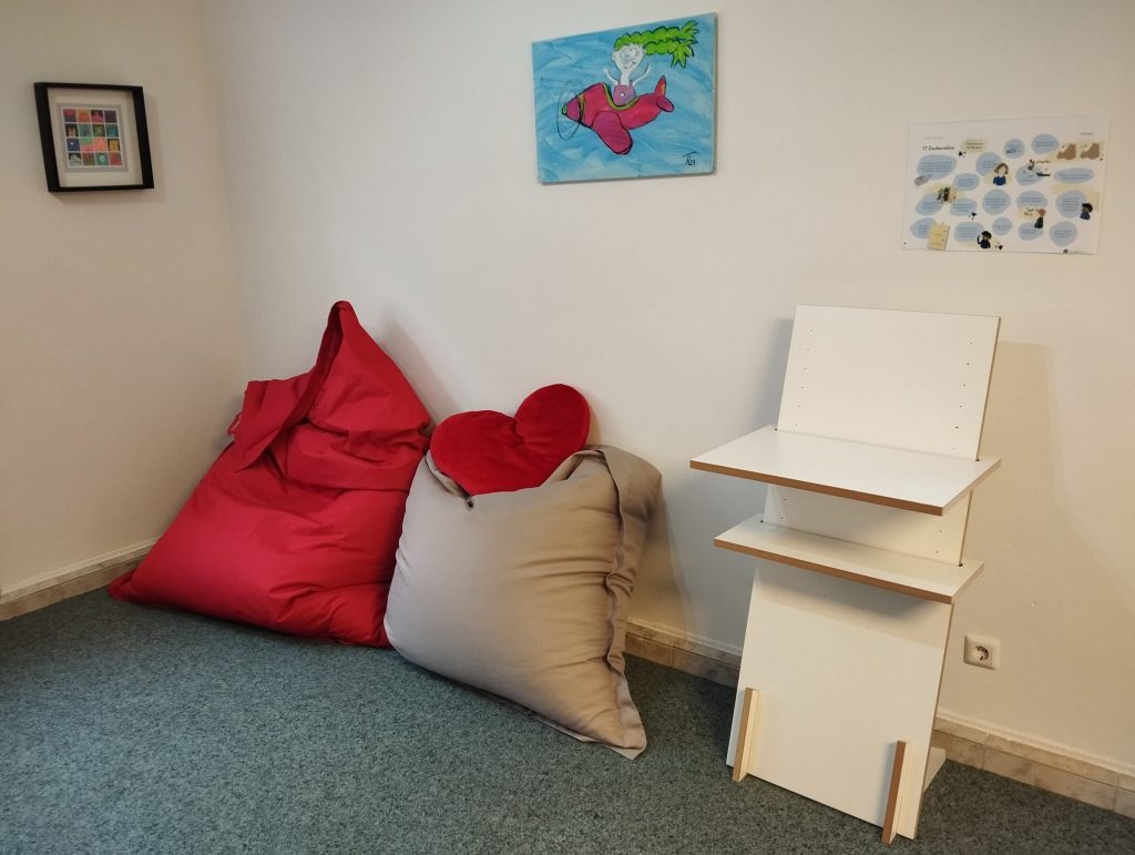 zwei Sitzsäcke daneben ein Stehpult an den Wänden drei Bilder