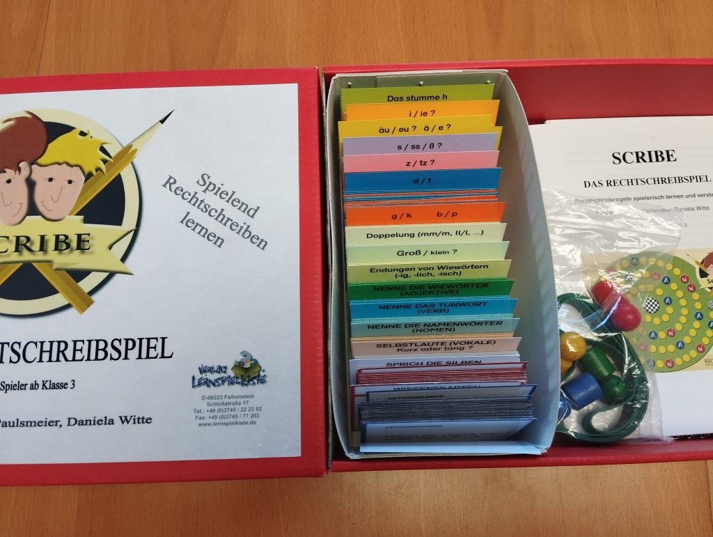 Karton mit Spielsteinen und Aufgabenkarten