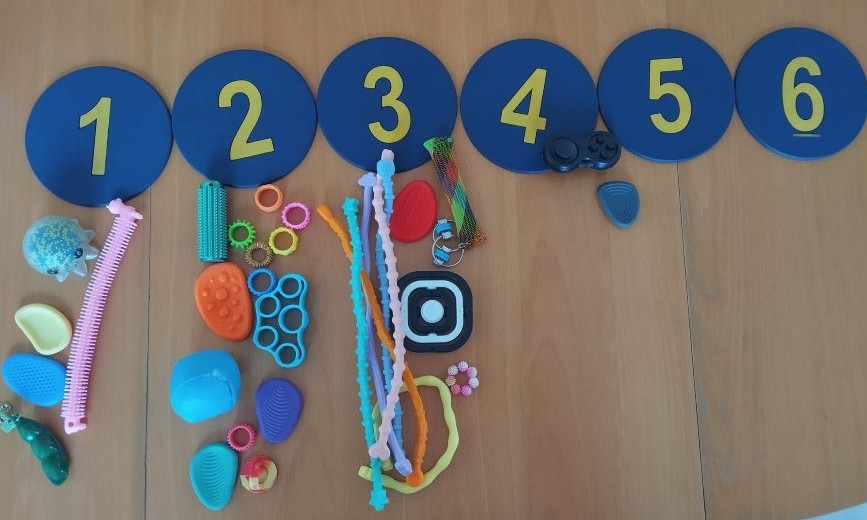 auf dem Tisch viele fidget toys darüber zahlen von 1 bis 6