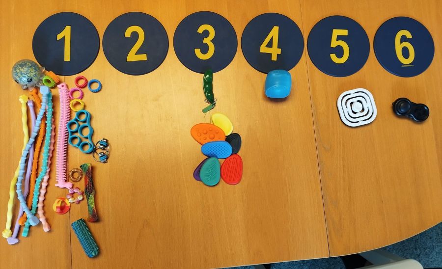 auf dem Tisch viele fidget toys darüber zahlen von 1 bis 6