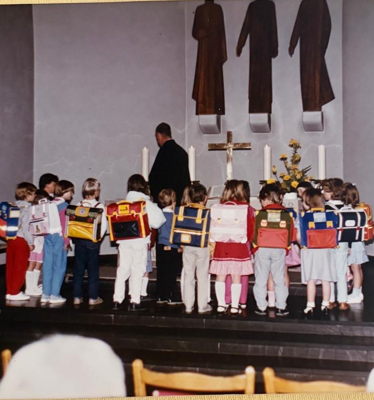 kinder mit Ranzen in einer Kirche